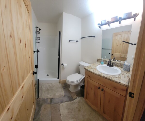 A bathroom with a shower, toilet, sink, and wooden cabinets. - Cozy Summer get away at Eagle Point (Beaver)