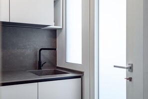 Eine moderne Küche mit integriertem Spülbecken, weißen Schränken und einem Fenster.