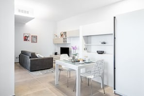 Ein modernes Wohnzimmer mit einer Couch, einem Esstisch mit Stühlen und einem Fernseher.