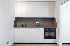 Eine moderne Küche mit weißen Schränken, einer schwarzen Arbeitsplatte und einem eingebauten Ofen.