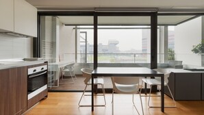 A modern kitchen with a dining area, large windows, and a view of the city. - GuestHost - Cozy Studio in Portello District (Milano)
