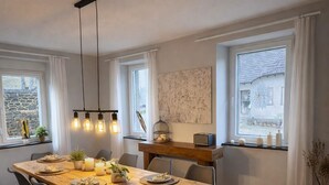 Een eethoek met een houten tafel, zwarte stoelen en hanglampen.