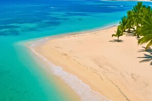 A beach with clear turquoise water, sandy shore, and palm trees. - Modern 2BR Condo in Playa Juan Dolio • AC • Near Beach (Playa Juan Dolio)
