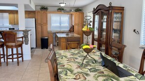 A kitchen with wooden cabinets, a dining table with a laptop, and a fruit basket. - A  Punta Gorda 1 Bed Waterfront 1st-Floor Condo -Walk to Fishermen’s Village (Punta Gorda)