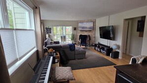 Un salon avec un piano, un canapé et un téléviseur.