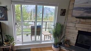 Une pièce dotée d’une grande porte-fenêtre coulissante donnant sur un patio, d’une cheminée et offrant une vue sur un paysage montagneux.