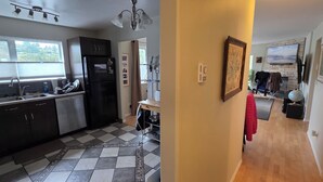 Une cuisine avec un réfrigérateur noir, un évier et une fenêtre. Un tapis à motifs recouvre le sol.