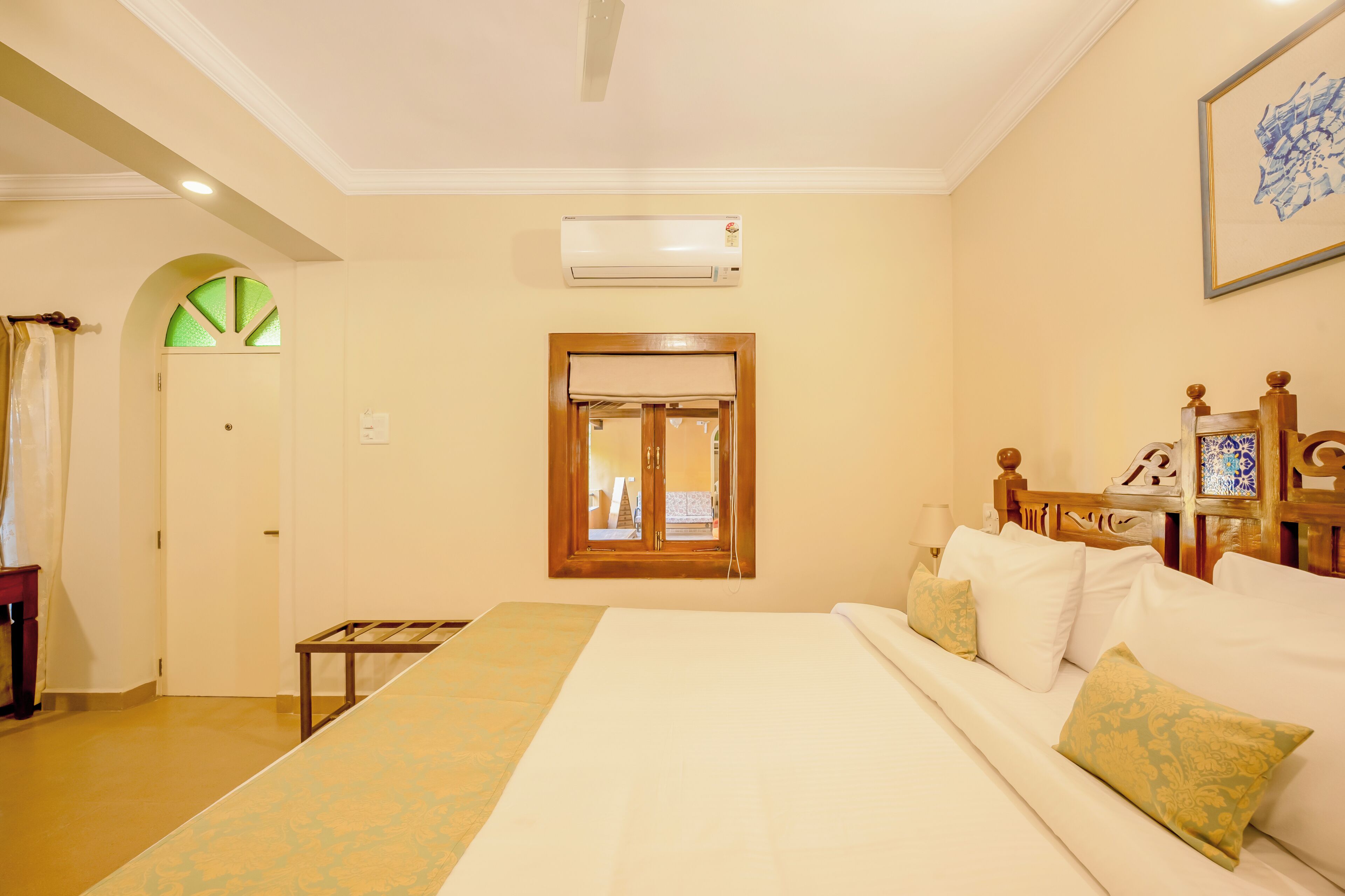 Habitación de hotel con cama, ventana con vistas, aire acondicionado y cabecero de madera.