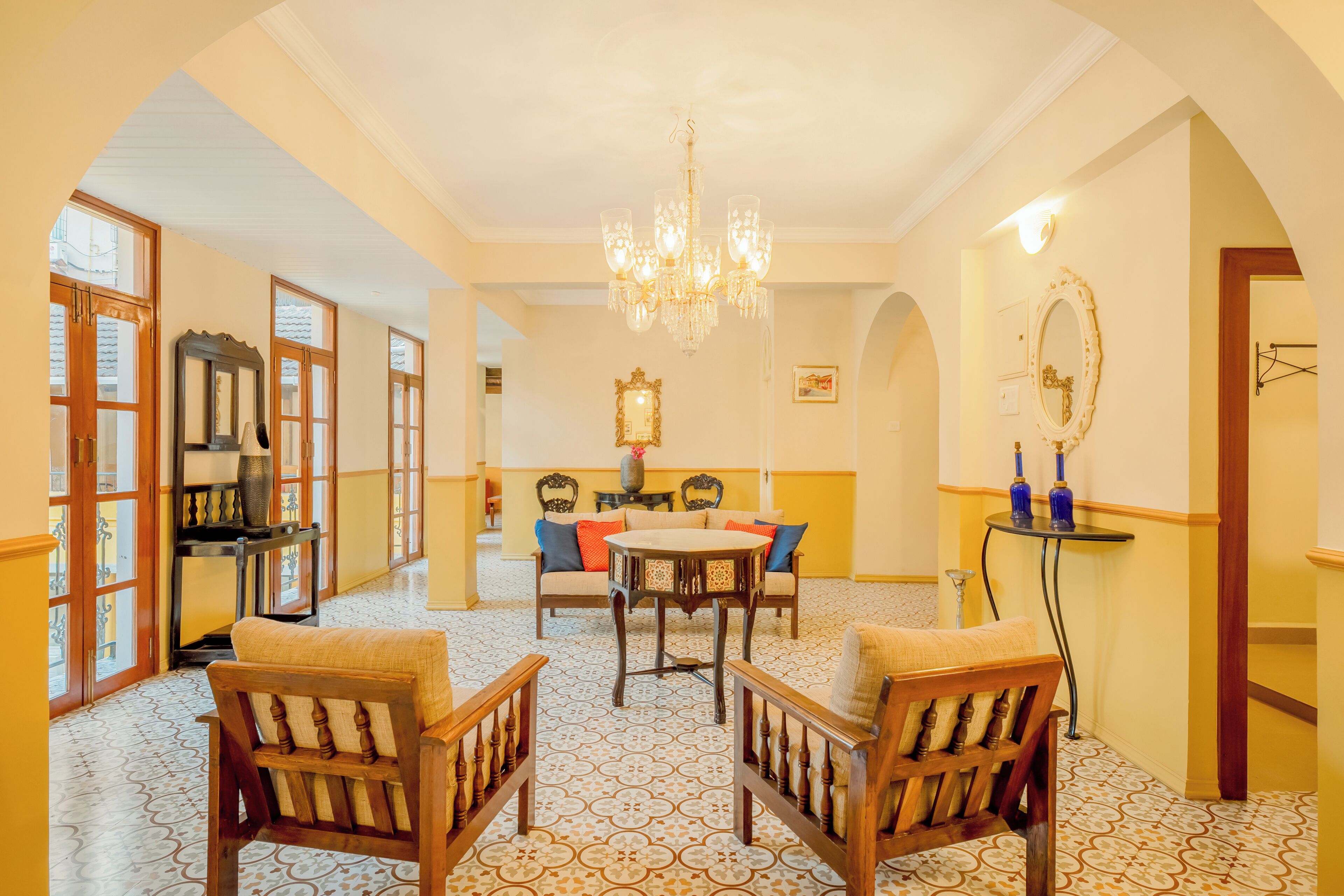 Un comedor con candelabro, sillas de madera, una mesa y suelo estampado.