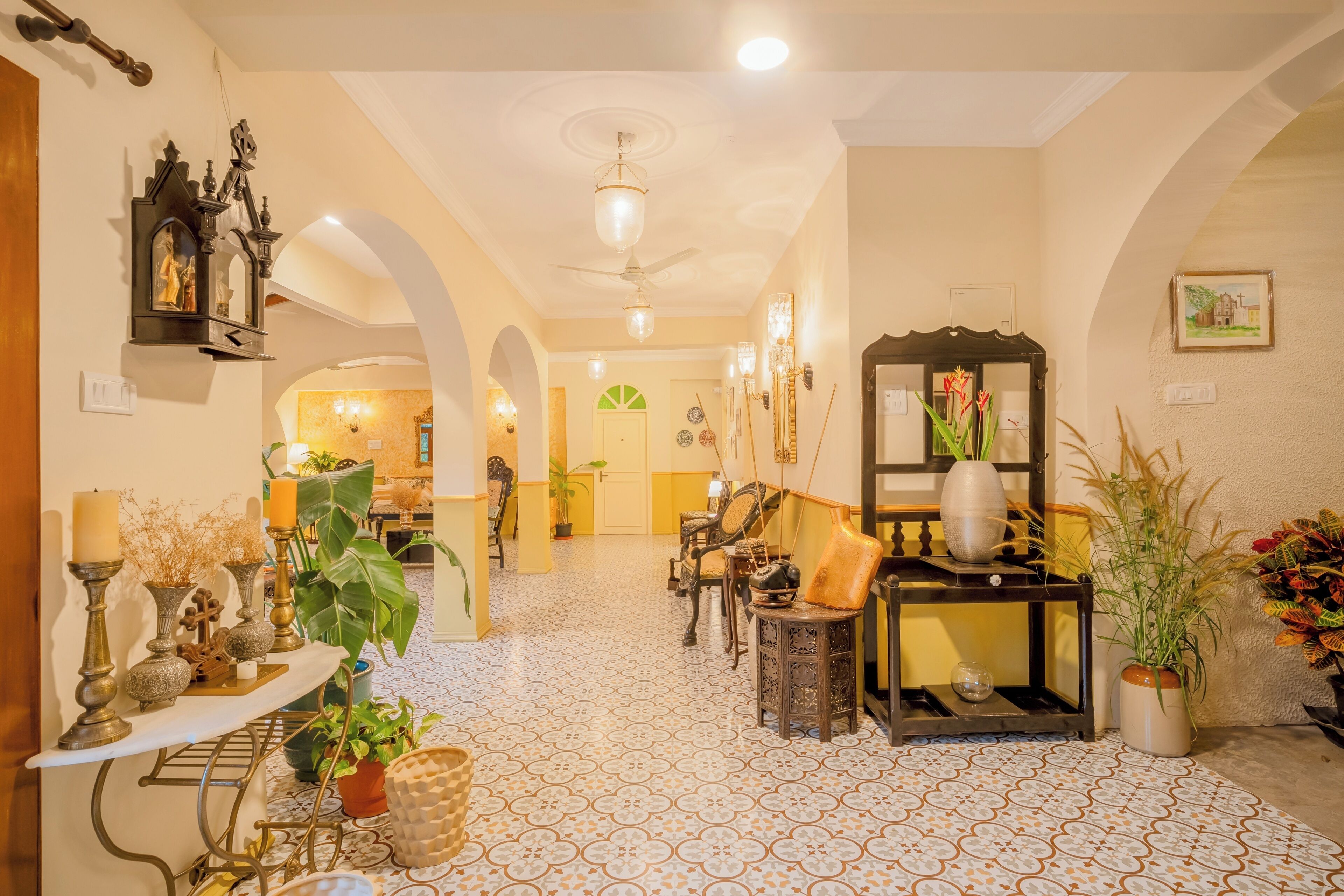 A spacious hallway with a tiled floor, a ceiling fan, and a variety of furniture including a console table, chairs, and a small side table.