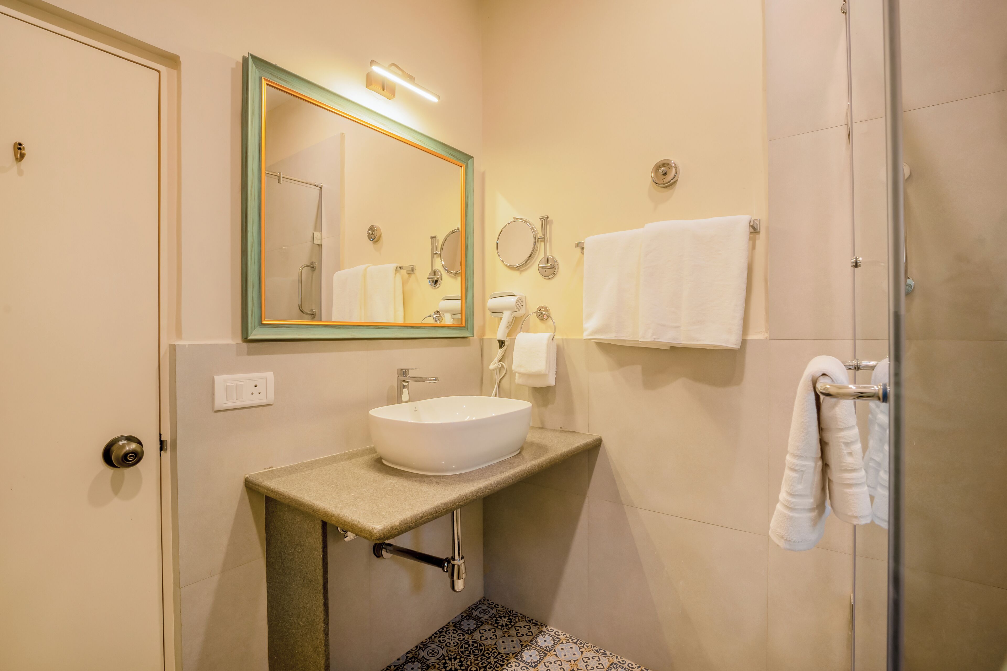 Ein Badezimmer mit Waschbecken, Spiegel, Handtuchhalter und Dusche.