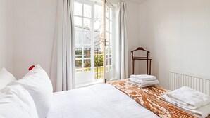 Ein Schlafzimmer mit einem Bett, einem Nachttisch mit Lampe und einem Fenster mit Vorhängen.