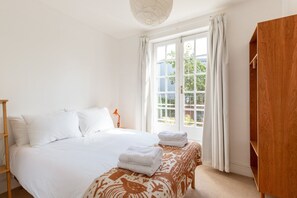 A bedroom with a bed, a wooden wardrobe, and a window with curtains. - Elegant Two Bed Near Shoreditch (London)