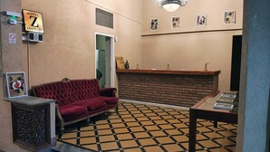 Een hotel lobby met een rode bank, een receptiebalie en een incheckbalie.