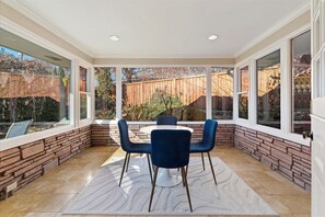 A sunroom with a stone wall, a round table, and four blue chairs. - Mid-Century Modern House, Boise Central Rim, Walk/Bike Downtown & Parks (Boise)