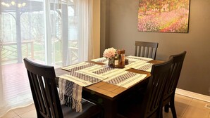 A dining area with a wooden table set for four, surrounded by chairs. A chandelier hangs above, and a painting adorns the wall. - Walk to Convention Centre, Restaurants, Falls! 3BR (Niagara Falls)