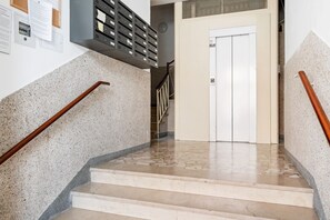 Eine Treppe mit Holzgeländer, eine weiße Tür oben und ein an der Wand befestigter Aktenschrank.