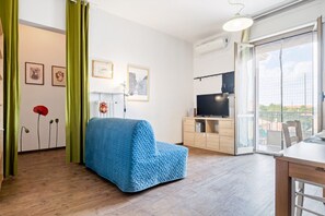 Ein modernes Wohnzimmer mit einem blauen Sofa, einem Fernseher und einem Essbereich.