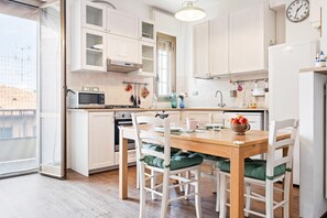 Eine moderne Küche mit weißen Schränken, einem Holztisch und grün gepolsterten Stühlen.