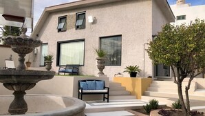 A modern building with a stone fountain, a bench, and a tree in the courtyard. - Charming 1 BR home w/private yard-walk to downtown (Durango)