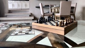 A chessboard set on a glass table in a modern living room with a kitchen in the background. - Charming 1 BR home w/private yard-walk to downtown (Durango)