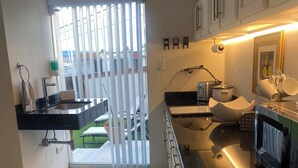 A modern kitchen with a black countertop, white cabinets, and a view of the outdoors through a sliding door. - Charming 1 BR home w/private yard-walk to downtown (Durango)