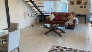 A spacious living room with a modern staircase, a chandelier, and a cozy seating area. - Charming 1 BR home w/private yard-walk to downtown (Durango)