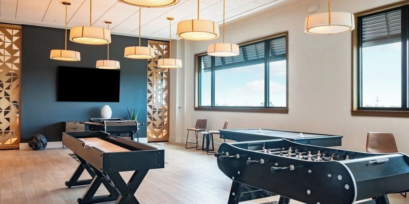 A modern room with a pool table, foosball table, and a large TV screen.