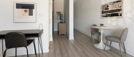 A modern, minimalistic room with a dining area, a small table with two chairs, and a kitchen visible in the background.