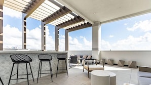 Una terraza en la azotea con zona de bar, asientos y vistas al cielo.