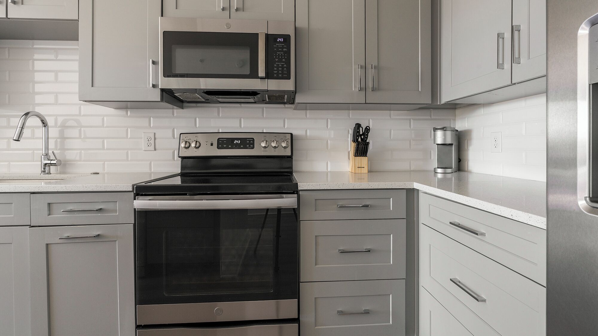 Una cocina moderna con electrodomésticos de acero inoxidable, armarios blancos y una salpicadera de azulejos.