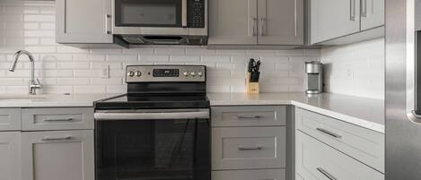 Una cocina moderna con electrodomésticos de acero inoxidable, armarios blancos y una salpicadera de azulejos.