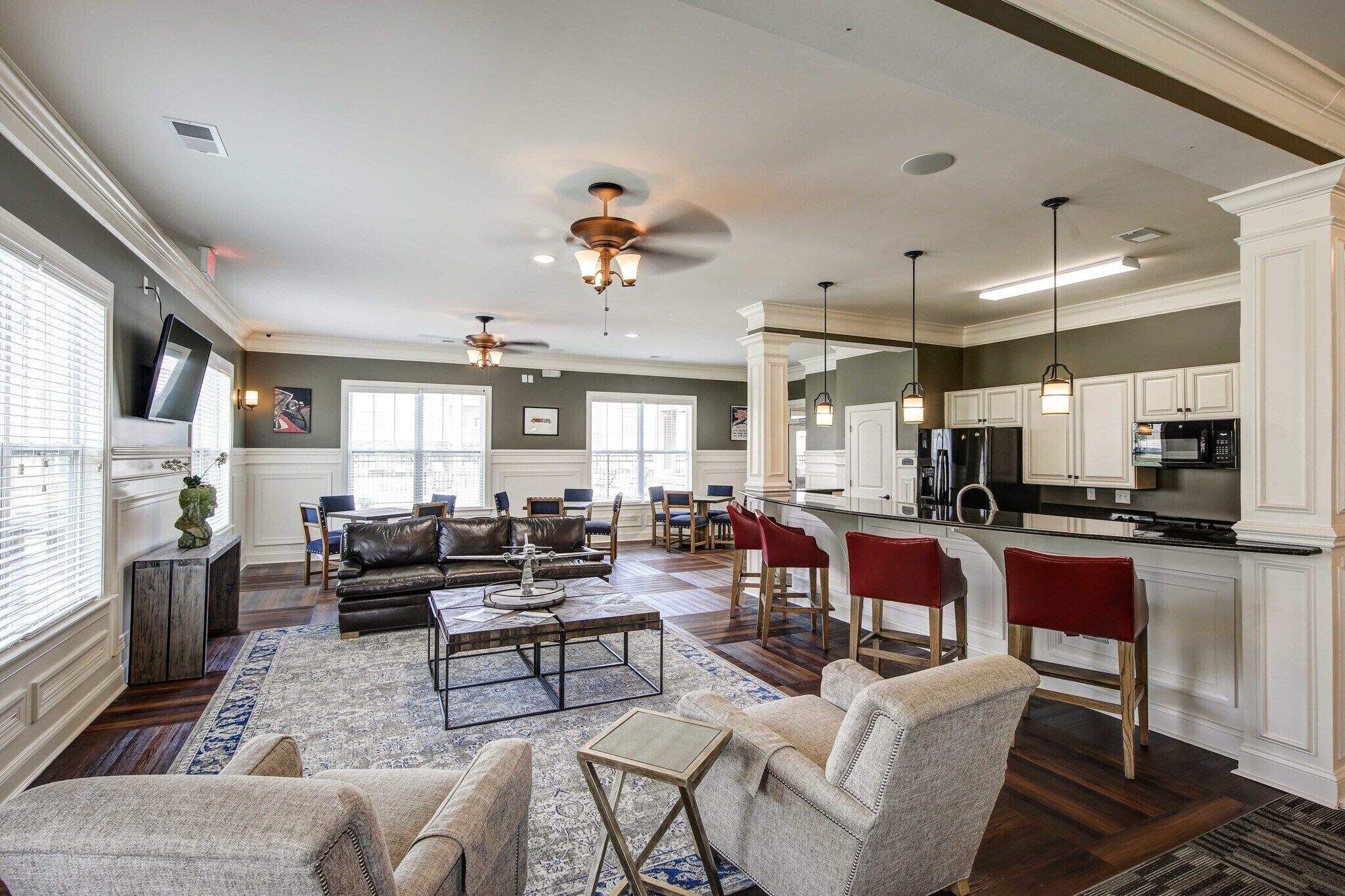 A spacious living room with a fireplace, a dining area with red chairs, and a kitchen with white cabinets.