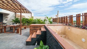 A rooftop terrace with wooden benches, a stone wall, and potted plants. - Penthouse with Rooftop Plunge Pool - Distant Ocean (Tulum)