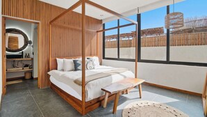 A modern bedroom with a four-poster bed, a wooden bench, and a large window offering a view of a wooden fence. - Penthouse with Rooftop Plunge Pool - Distant Ocean (Tulum)