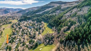 Wohngebiet mit Häusern, einem Golfplatz und bewaldeten Hügeln im Hintergrund.
