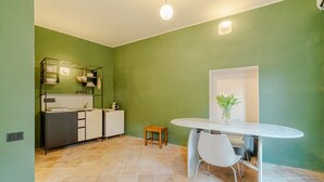 Eine moderne Küche mit weißer Arbeitsplatte, einem hölzernen Hocker und einem Esstisch mit Stühlen.