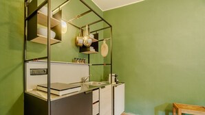 Eine Küche mit modernem Design, ausgestattet mit einer schwarzen Metallregaleinheit, einer Arbeitsplatte mit Spüle und einem hölzernen Hocker.