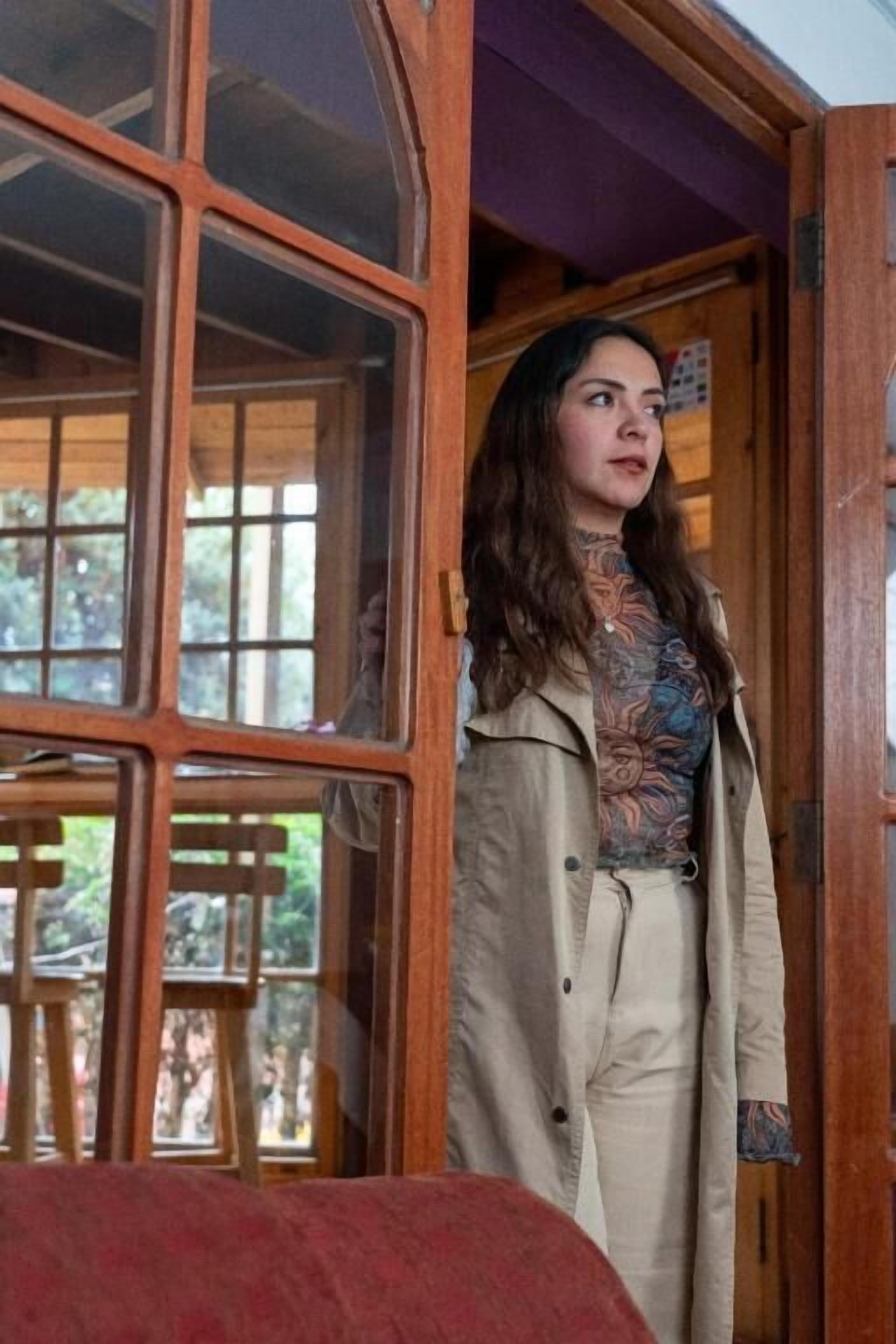 Una persona de pie en una habitación con paredes de madera y un ventanal grande.