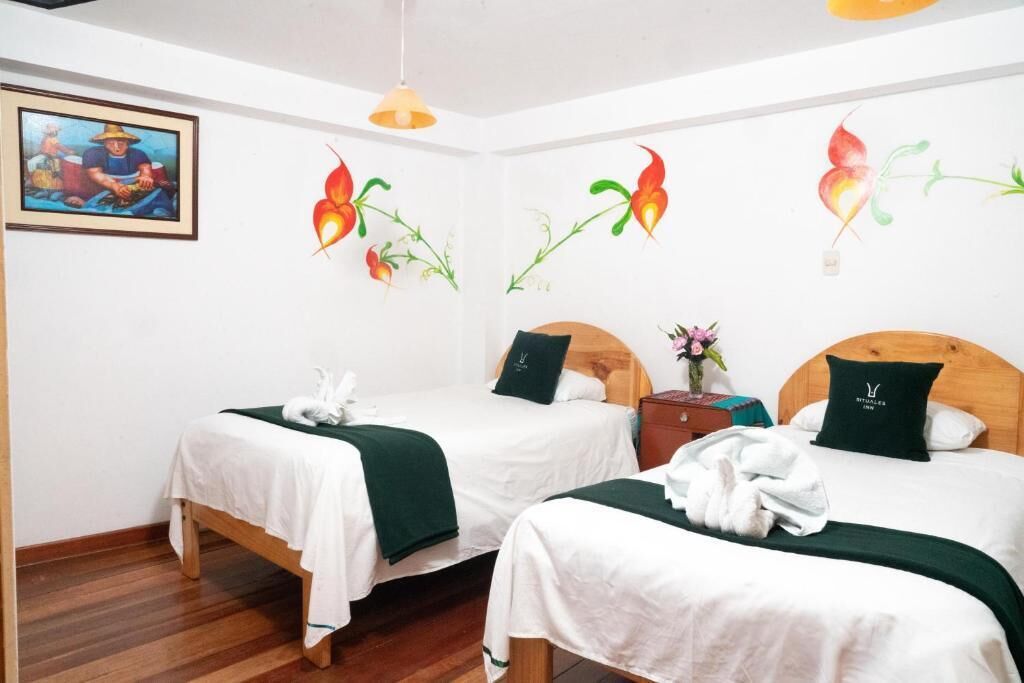 Una habitación de hotel con dos camas, cabeceros de madera, ropa de cama blanca y un cuadro en la pared.