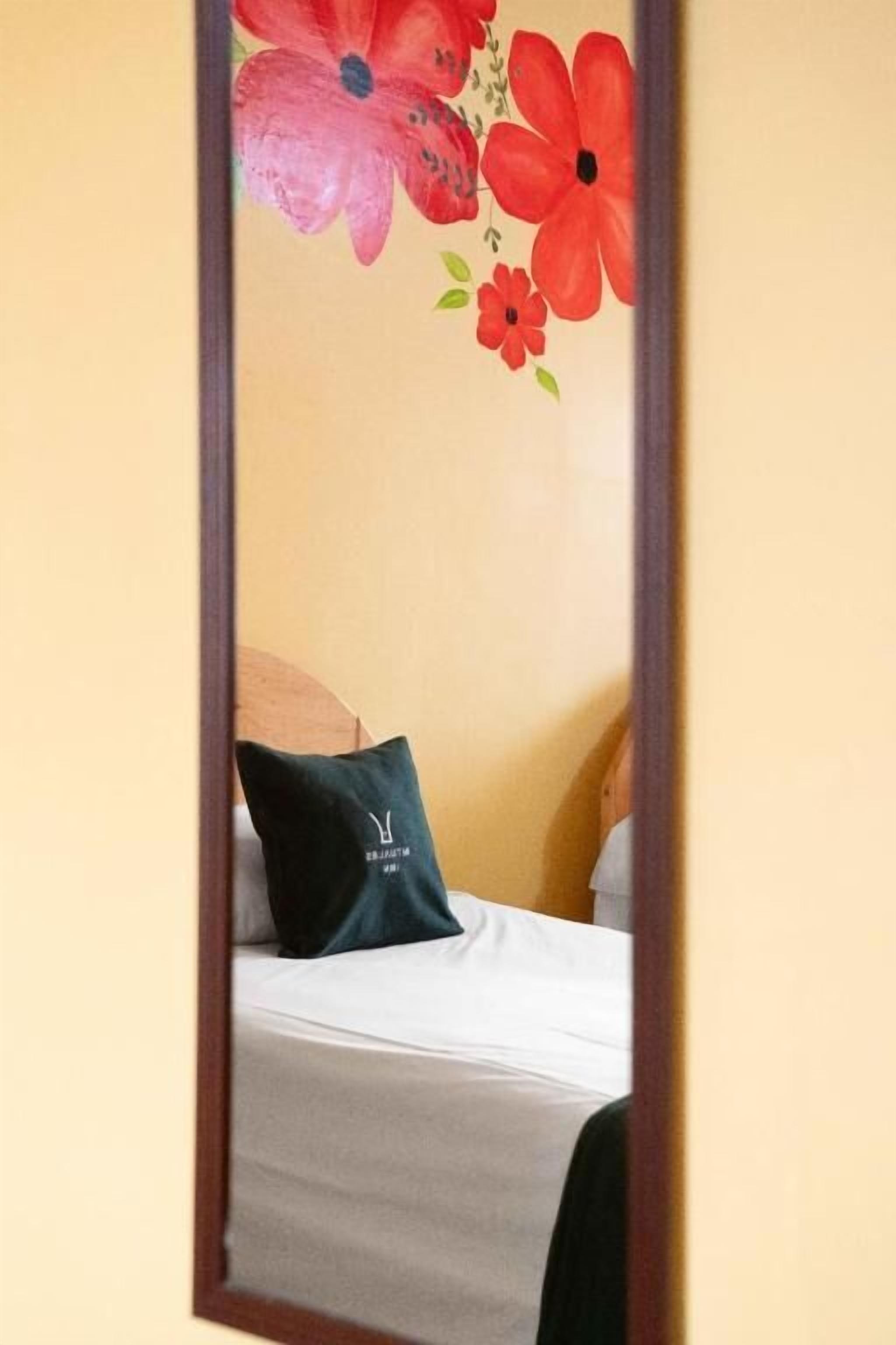 A bedroom with a bed, a pillow with a logo, and a wall with floral decorations.