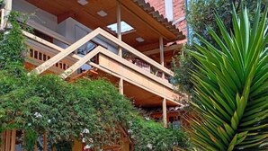 A building with a wooden balcony, a covered walkway, and a variety of plants. - Rituales Inn Santa Monica  (Cusco)