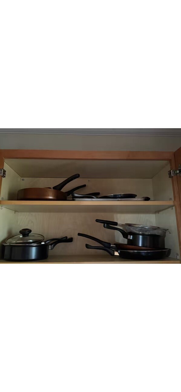 Un armario de cocina con tres estantes, cada uno con diferentes utensilios de cocina.