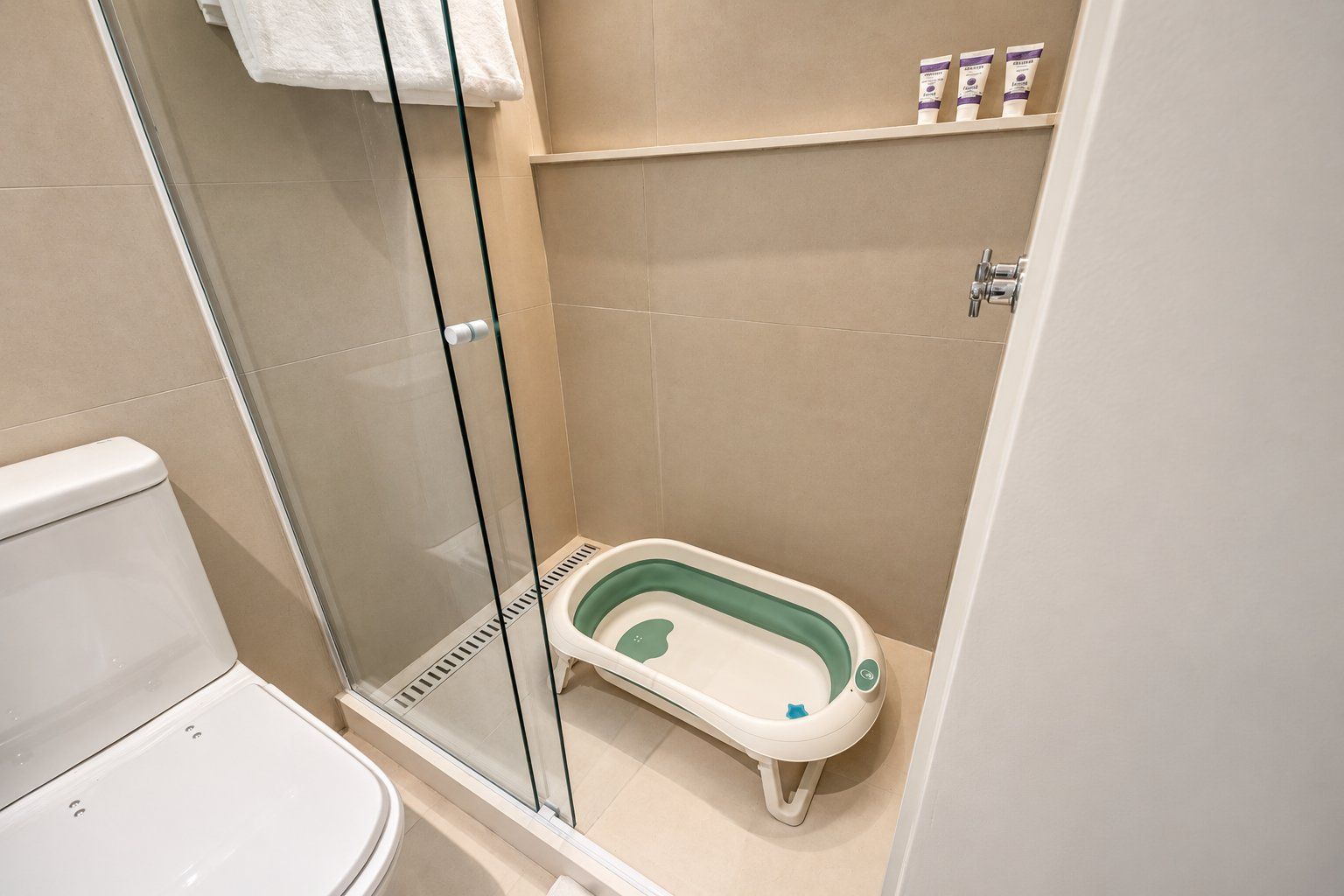 Un baño con cabina de ducha de vidrio, un inodoro blanco y una bañera pequeña verde y blanca.