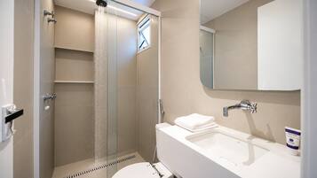 Ein modernes Badezimmer mit einer gläsernen Duschkabine, einem weißen Waschbecken und einer Toilette.