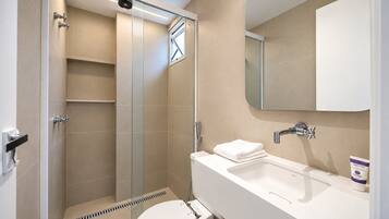 A modern bathroom with a glass-enclosed shower, a white sink, and a toilet.
