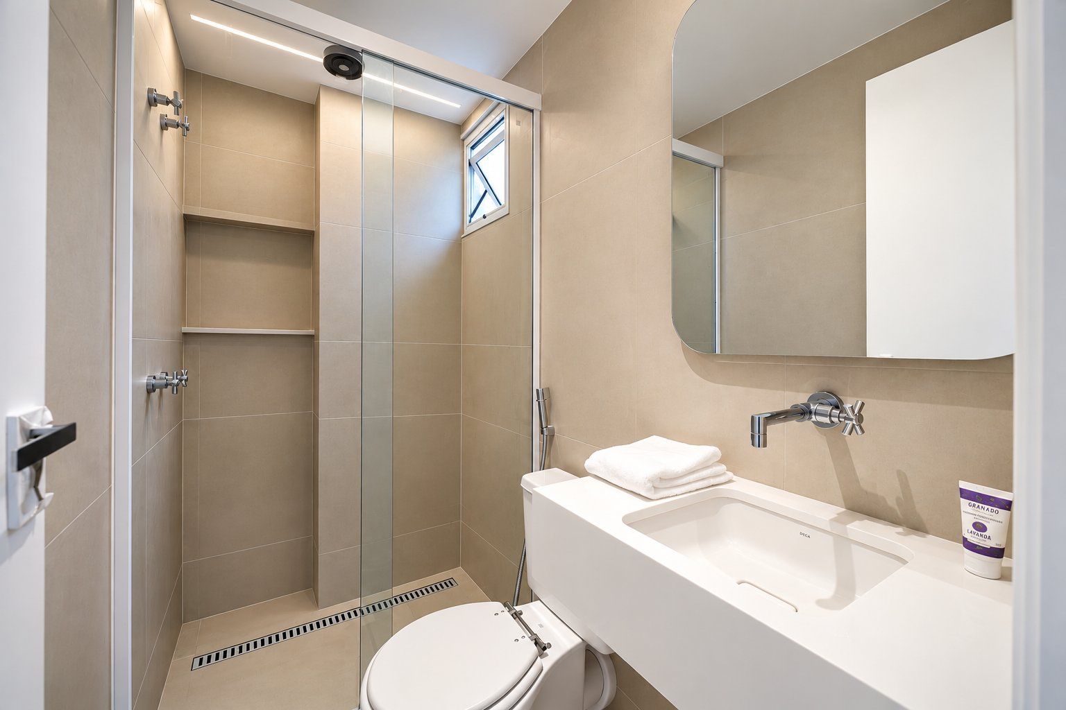 A modern bathroom with a glass-enclosed shower, a white sink, and a toilet.
