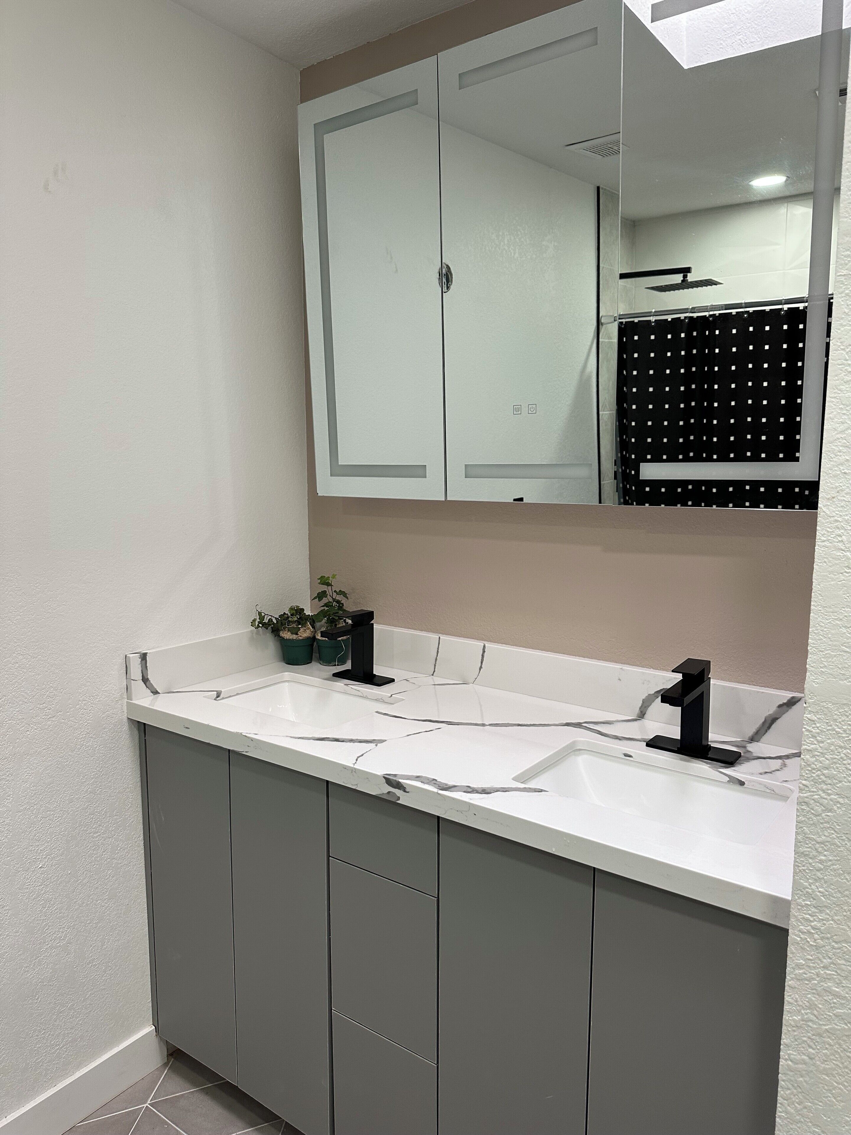 Un bagno con un mobile lavabo bianco, un rubinetto nero e uno specchio sopra il lavandino.