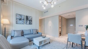 En moderne stue med en grå sofa, et hvidt sofabord og et spiseområde med et bord og stole.