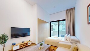 Una sala de estar moderna con una televisión de pantalla plana, un sofá, una mesa de centro y una planta.